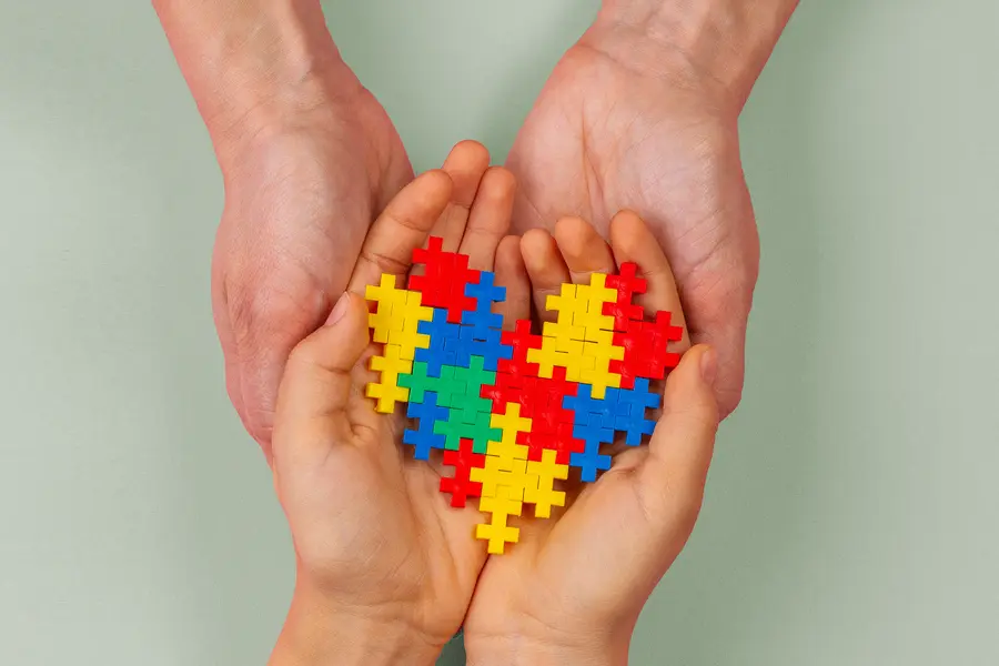 Autism-Clinic Two pairs of hands hold a puzzle in the shape of a heart. Get treatment for Autism from Proactive Wellness Centers in Loudoun County.