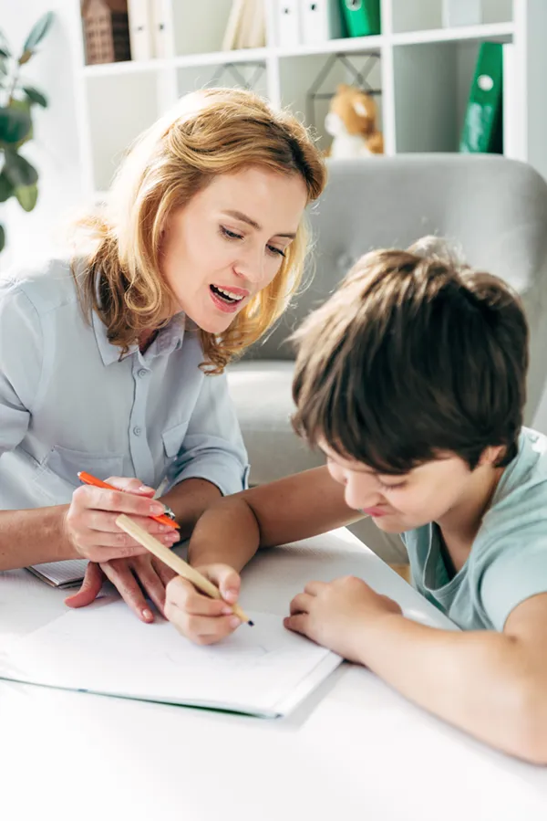 Autism-Treatment A therapist works with a child who is working on a drawing. Get treatment for Autism from Proactive Wellness Centers in Loudoun County.