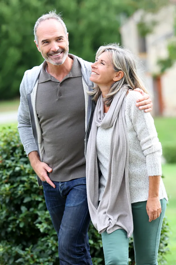 Bioidentical-Hormone-Therapy-Treatment A mature couple in gray toned clothes and jeans walk happily outside, happy with their successful bioidentical hormone treatments from Proactive Wellness Centers in Loudoun County.
