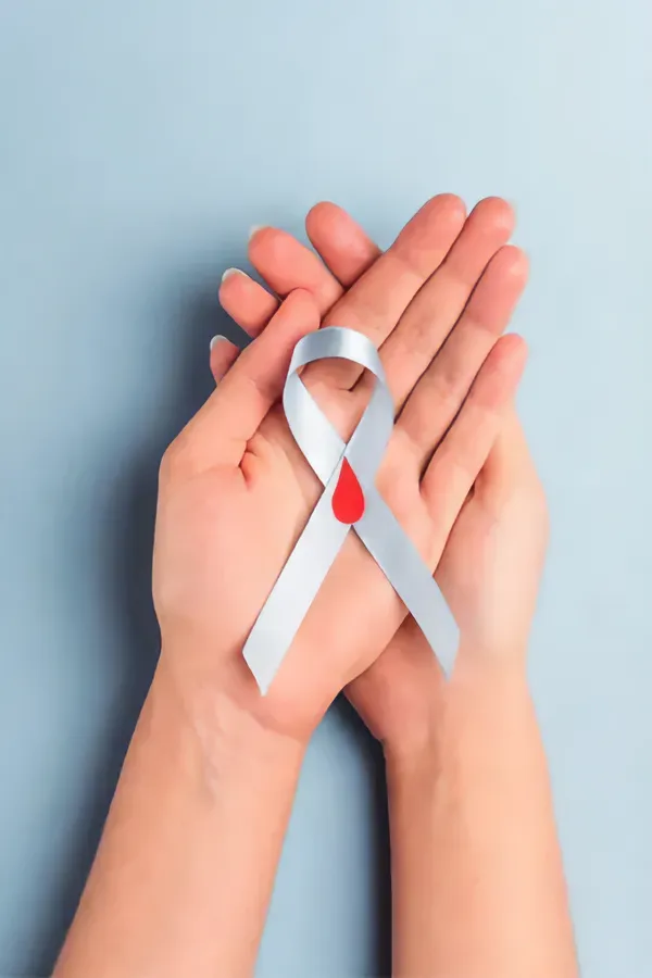 Diabetes-Treatment A woman's hands holding a white ribbon with a red drop symbol on it, symbolizing diabetes treatment from Proactive Wellness Centers in Loudoun County.