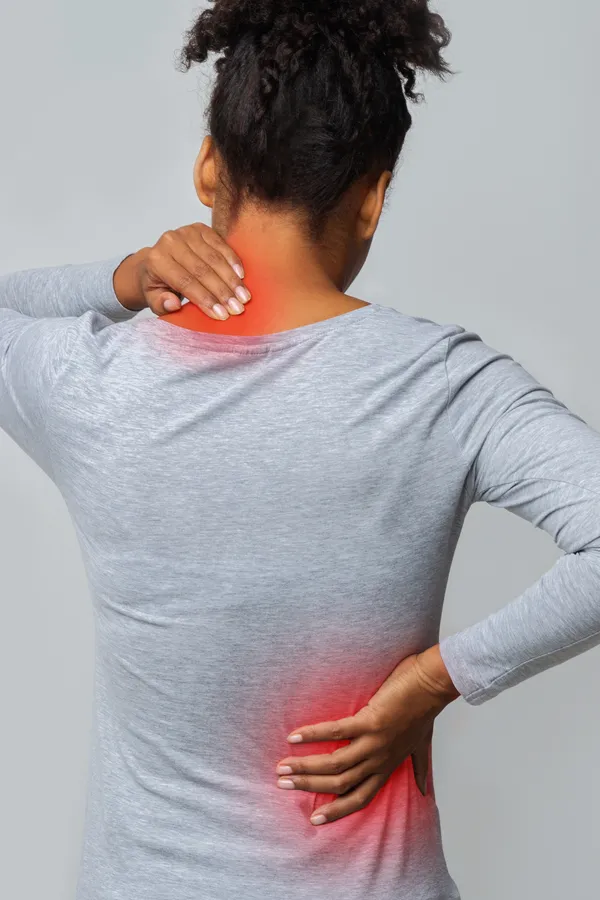 Fibromyalgia-Treatment An image from behind of a woman suffering from Fibromyalgia holding her hands on her neck and lower back. Get fibromyalgia treatment from Proactive Wellness Centers in Loudoun County.