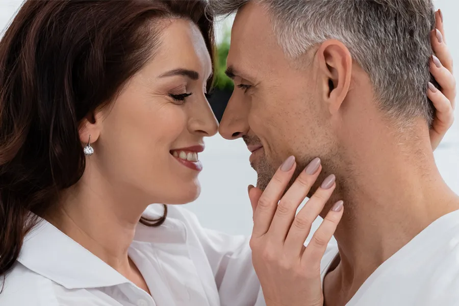 Gainswave-Clinic A middle-aged couple look into each others' eyes and grinning. Get Gainswave treatment for ED from Proactive Wellness Centers in Loudoun County.