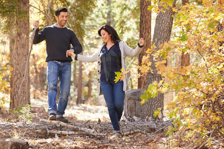 A couple happily hiking in the forest in fall. Get treatment for Lyme Disease from Proactive Wellness Centers in Loudoun County.