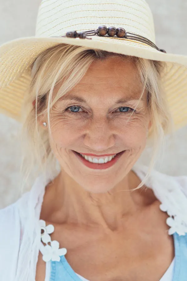 Menopause-Treatment A beautiful, smiling older woman with blonde hair and a sunhat, happy with menopause treatment from Proactive Wellness Centers in Loudoun County.