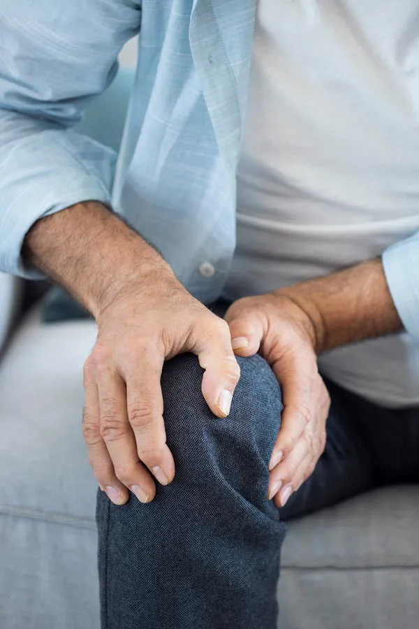 Osteoporosis-Pain A close-up of a man holding his knee while experiencing pain from osteoporosis. Get osteoporosis treatment from Proactive Wellness Centers in Loudoun County.