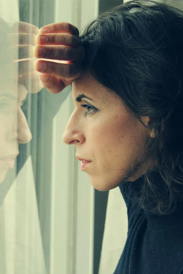 PCOS-Treatment A brunette woman in a thin dark turtleneck looks out the window with a serious expression, suffering from PCOS. Get treatment for Polycistic Ovarian Syndrome/PCOS from Proactive Wellness Centers in Loudoun County.