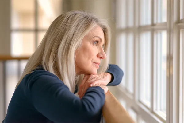 PMDD-Specialist A middle-aged woman with with a somber expression stares out the window. Get treatment for Premenstrual Dysphoric Disorder from Proactive Wellness Centers in Loudoun County.