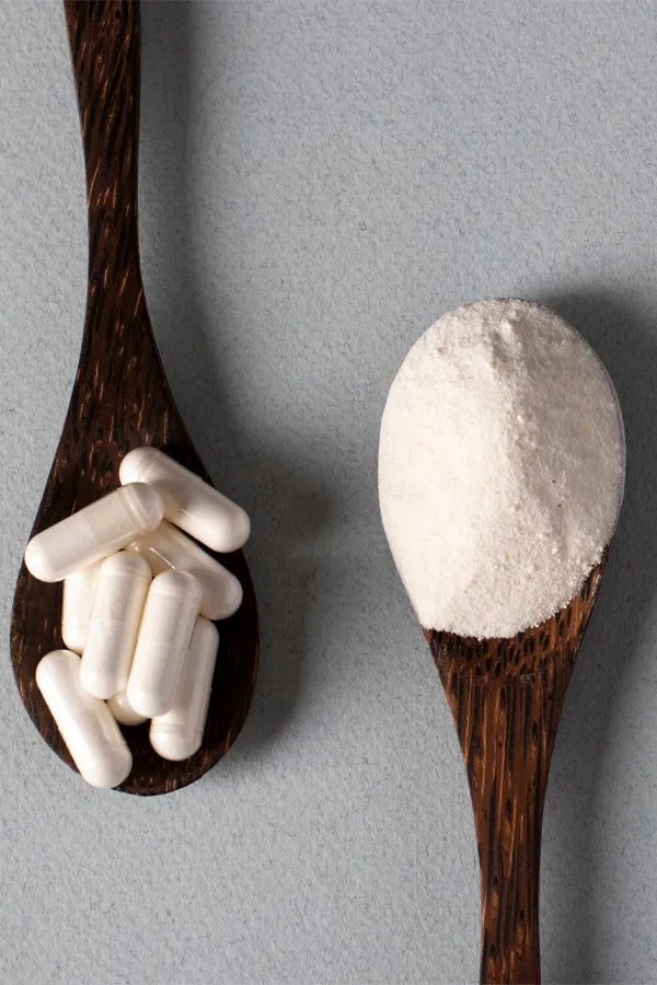 Peptide-Therapy-Treatment Two wooden spoons on a table, on with white powder and one with capsules, representing peptide therapy from Proactive Wellness Centers in Loudoun County.