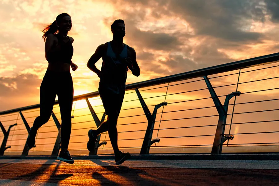 Performance-Enhancing-Peptides-Doctor A couple jogging on a bridge at sunrise, representing performance enhancing peptide therapy from Proactive Wellness Centers in Loudoun County.