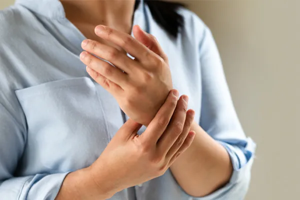Rheumatoid-Arthritis-Clinic Close up of a woman in a blue blouse rubbing her wrist. Get rheumatoid arthritis treatment from Proactive Wellness Centers in Loudoun County.
