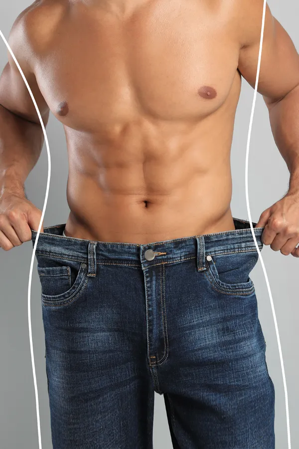 Semaglutide-Weight-Loss-Treatment A strong shirtless man in jeans holds the waistlines of his too-big jeans to show the success of semaglutide weight loss from Proactive Wellness Centers in Loudoun County.