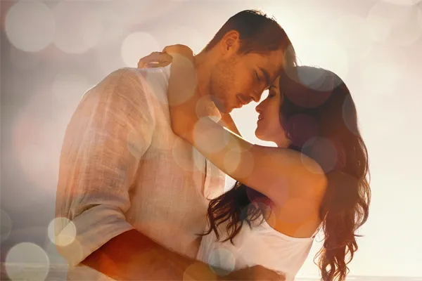 A couple in linen shirts standing in a sparkling light embraces each other with their foreheads touching and eyes closed, happy with their sexual wellness treatments from Proactive Wellness Centers in Loudoun County.