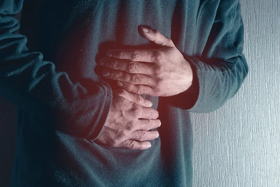 Ulcerative-Colitis-Clinic Close-up of the midsection of a man in a green sweater clutching his gut in pain. Get treatment for Ulcerative Colitis from Proactive Wellness Centers in Loudoun County.